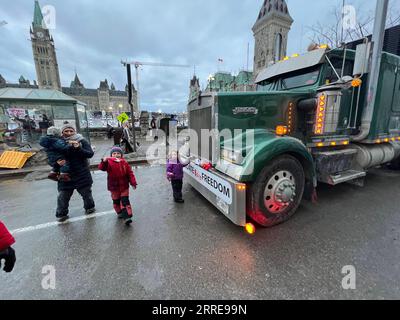 220211 -- OTTAWA, 11. Februar 2022 -- Menschen laufen an einem LKW auf der Wellington Street in Ottawa, Kanada, 10. Februar 2022 vorbei. Der Ottawa Police Service sagte am Donnerstag, dass die Polizei 25 Menschen verhaftet und 1.775 Tickets ausgestellt habe, um die unrechtmäßigen Demonstrationen in den Innenstadtgebieten zu beenden. Der Freedom Convoy 2022 begann am 29. Januar als Kundgebung von Truckern gegen die Forderung, dass kanadische Lkw-Fahrer, die die Grenze in die Vereinigten Staaten überqueren, ab Mitte Januar vollständig geimpft werden müssen. KANADA-OTTAWA-TRUCKER-PROTEST LinxWei PUBLICATIONxNOTxINxCHN Stockfoto