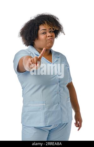 Vertikales Porträt einer venezolanischen afro-lateinischen Ärztin, die in blauer Uniform steht, mit dem Finger nach oben auf die Kamera schaut und die Medizin missbilligt Stockfoto