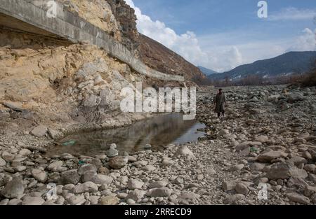 220218 -- SRINAGAR, 18. Februar 2022 -- Ein Mann geht in einem trockenen Bach in einem Dorf im Bezirk Anantnag, etwa 94 km südlich von Srinagar, der Sommerhauptstadt des von Indien kontrollierten Kaschmirs, 18. Februar 2022. Ein vertikales Senken, das sich in der Mitte eines Flussbettes entwickelt hat, hat einen Süßwasserstrom im von Indien kontrollierten Kaschmir gefressen, sagten Beamte am Donnerstag. Das Senkenloch hat den gesamten Lauf des Bachwassers in es abgeführt und den flussabwärts gelegenen Teil trocken gelassen, wodurch Forellenfische in großer Zahl getötet wurden. Sie hat auch unermessliche Schäden an Wassertieren verursacht. KASCHMIR-SRINAGAR-VERTIKALES SINKHOLE JA Stockfoto