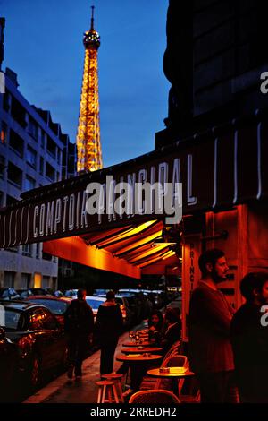 Der Eiffelturm erleuchtete in der Abenddämmerung vor einem blauen Nachthimmel, die Markise des Comptoir Principal auf Grenelle leuchtend rot, Spätsommer, Abend in Paris Stockfoto