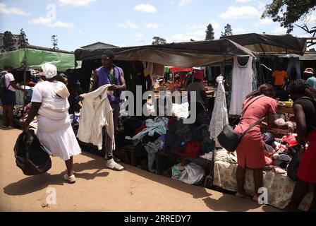 220222 -- HARARE, 22. Februar 2022 -- Batsirai Tsombori, ein Second-Hand-Bekleidungsverkäufer, spricht mit einer Frau auf seinem Straßenmarkt in Mbare, Harare, Simbabwe, 8. Februar 2022. Für viele Besucher scheint Mbare, eine der einkommensschwachen Siedlungen von Harare, eine chaotische und schmutzige Gemeinde zu sein. Die verstaubten Straßen der Gegend, die verfallenen Wohnhäuser und die überfüllten Straßenmärkte tun der Siedlung keinen Gefallen. Trotz all des Chaos, das Mbare auszeichnet, zeigt ein genauerer Blick, dass inmitten all dieses Chaos fleißige Bürger ihr Bestes geben, um in einer schwierigen wirtschaftlichen Umgebung zu leben Stockfoto