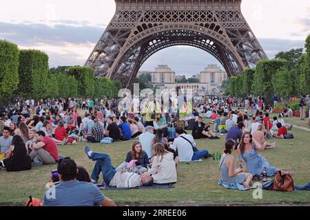 Souvenirverkäufer, die auf den Champs de Mars arbeiten, verkaufen Souvenirs, Bier und Wein an Touristen, die am Abend ein Picknick machen und auf die Lichtshow im Eiffelturm warten Stockfoto