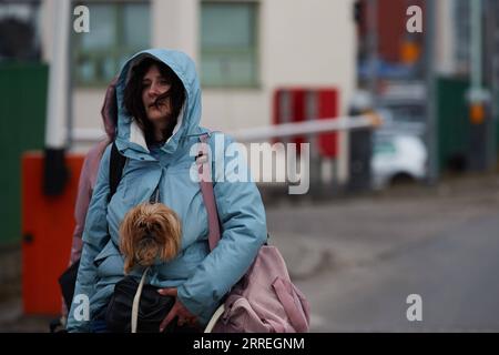 220301 -- MEDYKA, 1. März 2022 -- Eine Frau geht mit einem Hund an der Grenze in Medyka, Polen, am 28. Februar 2022. POLEN-MEDYKA-MENSCHEN VERLASSEN DIE UKRAINE MengxDingbo PUBLICATIONxNOTxINxCHN Stockfoto