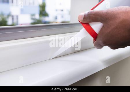 Nahaufnahme der Person Hand mit Silikon-dichtmittel Abdichten mit Silikon Gewehr am Fenster Stockfoto