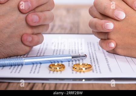 Die Paar Hand mit Scheidung und Goldene Hochzeit Ringe auf hölzernen Schreibtisch Stockfoto