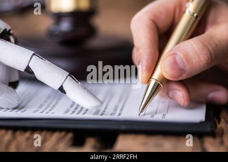Roboterhand Unterstützung der Person, die für die Unterzeichnung dieses Dokuments Holzschreibtisch im Gerichtssaal Stockfoto