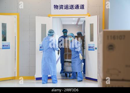 220326 -- SHANGHAI, 26. März 2022 -- medizinische Arbeiter liefern Versorgungsgüter an eine zentrale Quarantänezone des nördlichen Krankenhauses des Ruijin Krankenhauses im ostchinesischen Shanghai, 25. März 2022. Das Krankenhaus wurde kürzlich renoviert und in Betrieb genommen. Mehr als 1.700 leichte und asymptomatische COVID-19-Patienten wurden hier behandelt. Gegenwärtig wurden eine Reihe von medizinischen Einrichtungen in Shanghai in zentrale Quarantänezentren für leichte und asymptomatische Patienten umgewandelt. CHINA-SHANGHAI-COVID-19-QUARANTINE CN DingxTing PUBLICATIONxNOTxINxCHN Stockfoto