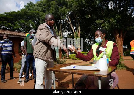 220326 -- HARARE, 26. März 2022 -- Ein Mitarbeiter überprüft die Körpertemperatur eines Wählers in einer Wahlstation in Harare, Simbabwe, am 26. März 2022. Simbabwe führte am Samstag eine entscheidende Nachwahl durch, die durch eine niedrige Wahlbeteiligung in vielen Wahlkreisen gekennzeichnet war. Foto von /Xinhua ZIMBABWE-HARARE-BY-ELECTION ShaunxJusa PUBLICATIONxNOTxINxCHN Stockfoto