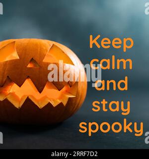 Komposition aus „Keep ruhig und unheimlich bleiben“-Text und halloween-Kürbis auf schwarzem Hintergrund Stockfoto