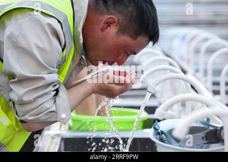 220408 -- HONG KONG, 8. April 2022 -- Ein Arbeiter kühlt sein sonnenverbranntes Gesicht mit kaltem Wasser auf der Baustelle eines Notfallkrankenhausprojekts in Hong Kong, Südchina, 9. März 2022. Die Anlagen, die in der ersten Bauphase eines Notfallkrankenhausprojekts errichtet wurden, wurden am Donnerstag mit Unterstützung der chinesischen Zentralbehörden den zuständigen Abteilungen in der Sonderverwaltungsregion Hongkong übergeben. Die fertiggestellten Einrichtungen bestehen aus 500 Unterdruckbetten, darunter 32 Intensivstationen und zwei OP-Räumen. Der erste Bauabschnitt des Krankenhauses begann am 6. März und Stockfoto