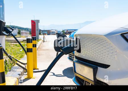 Laden des Elektrofahrzeugs im Freien. Nahansicht eines aufladbaren Elektroautos. EV-Ladegerätestecker am Fahrzeug. Stockfoto
