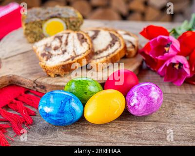 Traditionelles rumänisches ostergericht Cozonac oder Süßbrot auf Holztisch und farbige ostereier und weiße Narzissenblüten Stockfoto