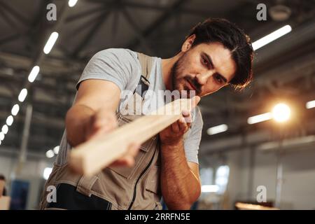 Junger Zimmermann sucht und wählt Holzbohle in einer Werkstatt in einer Holzfabrik Stockfoto