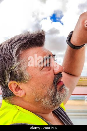 Mann in gelber reflektierender Weste, der an einem sonnigen Tag einen technischen Check durchführt Stockfoto