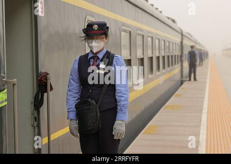 220430 -- KASHGAR, 30. April 2022 -- Zugbegleiter warten auf Passagiere auf dem Bahnsteig neben einem langsamen Zug nach Hotan in der nordwestchinesischen Autonomen Region Xinjiang Uygur, 27. April 2022. Da Hochgeschwindigkeitszüge in vielen Teilen Chinas durch Bahnhöfe sausen, bedienen die scheinbar veralteten, rumpelnden Schnellzüge weiterhin Bewohner abgelegener Gebiete mit stabilen Ticketpreisen und Dienstleistungen. Obwohl China das am weitesten entwickelte Hochgeschwindigkeitsbahnnetz der Welt beherbergt, betreibt es regelmäßig 81 Langsamzüge. Die Züge 7556/7557 und 7558/7555 verkehren zwischen Xinjiangs Hauptstadt Uru Stockfoto