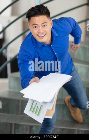Fröhlicher junger Geschäftsmann, der Ihnen Papiere gibt Stockfoto