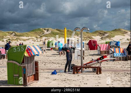 Strandleben am feinen Sandstrand von Norddorf auf der Nordseeinsel Amrum ein Windsurfer unter der Dusche Stockfoto