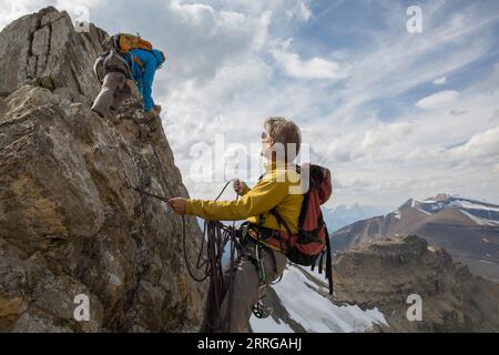 Bergsteiger sichern Teamkollege auf dem Gipfelgrat Stockfoto