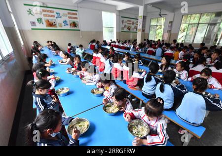 220520 -- DU AN, 20. Mai 2022 -- Kinder essen in der Sanzhiyang Elementary School in du an Yao Autonomous County, südchinesische autonome Region Guangxi Zhuang, 18. Mai 2022. Vor 11 Jahren wuchsen die Kinder von Sanzhiyang auf einer Diät aus gedämpftem Reis und Sojabohnen auf, eines der wenigen Dinge, die dort wachsen würden. Damals war Unterernährung bei den Schülern üblich. 2011 begann ein Plan zur Verbesserung der Ernährung von Schülern in ländlichen Gebieten, der Schülern in Schulen wie Sanzhiyang nahrhafte Mahlzeiten anbietet. Heute serviert die gut ausgestattete Mensa der Sanzhiyang Elementary School sorgfältig ausgewogene Mahlzeiten Stockfoto