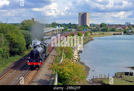 Der Dorset Coast Express Dampfzug von London nach Weymouth überquert den Redbridge Causeway, der die Mündung des River Test überquert. Stockfoto