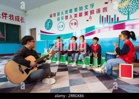 220525 -- HARBIN, 25. Mai 2022 -- Lehrer Zhang Yu 1st L und Kinder in der Musikklasse üben für Bandauftritte an der Renmin Town Central Primary School in Anda, nordöstliche Provinz Heilongjiang, 24. Mai 2022. Die Musikklasse der Grundschule wurde im April 2019 gegründet. Lehrer der Klasse passen die Texte beliebter Lieder so an, dass sie für Kinder zum Singen geeignet sind, und unterrichten sie dann während der Mittagspause oder der Club-Aktivität. Die Chor-Videos der Kinder wurden auf kurzen Videoplattformen veröffentlicht, die von vielen Netizens beliebt waren und über 1 Million Fans verdienten. Wi Stockfoto