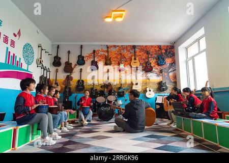 220525 -- HARBIN, 25. Mai 2022 -- Lehrer Zhang Yu und Kinder in der Musikklasse üben für Bandauftritte an der Renmin Town Central Primary School in Anda, nordöstliche Provinz Heilongjiang, 24. Mai 2022. Die Musikklasse der Grundschule wurde im April 2019 gegründet. Lehrer der Klasse passen die Texte beliebter Lieder so an, dass sie für Kinder zum Singen geeignet sind, und unterrichten sie dann während der Mittagspause oder der Club-Aktivität. Die Chor-Videos der Kinder wurden auf kurzen Videoplattformen veröffentlicht, die von vielen Netizens beliebt waren und über 1 Million Fans verdienten. Mit dem Stockfoto