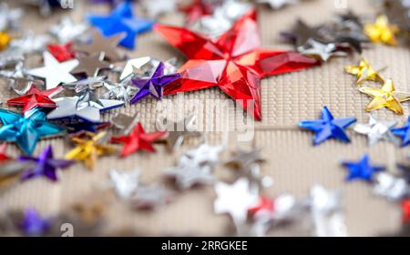 Hintergrund der Weihnachtsfeiertage. Dekorative, mehrfarbige Sterne. Sterne Konfetti abstrakt auf dem Tisch. Stockfoto