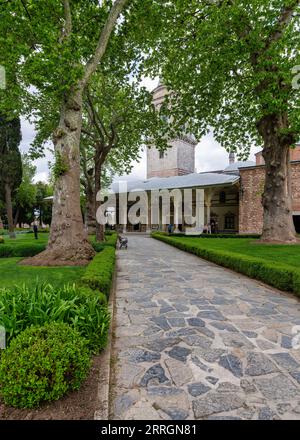 Istanbul, Türkei - 11. Mai 2023: Steinsteg, umgeben von üppigen Bäumen, führt zum Gebäude des Kaiserlichen Rates im Innenhof des Topkapi-Palastes Stockfoto