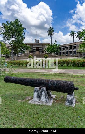 Eine Kanone aus der Kolonialzeit auf dem Independence Plaza in der Hauptstadt Belmopan, Belize. Das Gebäude der Nationalversammlung ist dahinter. Stockfoto