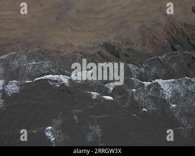 Eine ruhige Strandszene mit großen rollenden Wellen und weiten Sandstränden. Stockfoto