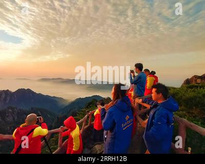 220607 -- HUANGSHAN, 7. Juni 2022 -- Touristen sehen den Sonnenaufgang auf Mount Huangshan, 5. Juni 2022. Der Mount Huangshan, auch bekannt als der gelbe Berg, liegt in der ostchinesischen Provinz Anhui und ist bekannt für seine herrliche Naturlandschaft, einschließlich massiver Granitfelsen und alter Kiefern, die oft durch Wolken- und Nebeleffekte noch verstärkt werden. Die Anlage verfügt über zahlreiche imposante Gipfel, von denen viele eine Höhe von 1.000 Metern überschreiten, wobei der höchste, der berühmte Lianhua Peak Lotus Peak, bis zu 1.864 Meter hoch ist. Huangshan ist auch berühmt für seine alten Wege, Brücken und Brücken Stockfoto