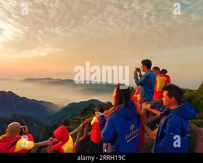 220607 -- HUANGSHAN, 7. Juni 2022 -- Touristen sehen den Sonnenaufgang auf Mount Huangshan, 5. Juni 2022. Der Mount Huangshan, auch bekannt als der gelbe Berg, liegt in der ostchinesischen Provinz Anhui und ist bekannt für seine herrliche Naturlandschaft, einschließlich massiver Granitfelsen und alter Kiefern, die oft durch Wolken- und Nebeleffekte noch verstärkt werden. Die Anlage verfügt über zahlreiche imposante Gipfel, von denen viele eine Höhe von 1.000 Metern überschreiten, wobei der höchste, der berühmte Lianhua Peak Lotus Peak, bis zu 1.864 Meter hoch ist. Huangshan ist auch berühmt für seine alten Wege, Brücken und Brücken Stockfoto