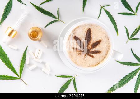 Medizinisches Cannabis Hanf Kaffee Latte. Tasse cremiger geschlagener Kaffee mit Cannabisöltropfen und gezeichnetem Blatt, mit Hanfblättern auf weißem Hintergrund Stockfoto
