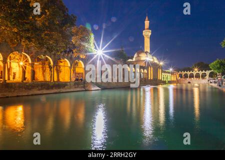 Sanliurfa, Türkei - 19. Juni 2023 : Balıklıgöl (Balık-See) und Rizvaniye-Moschee in wunderschöner Sonnenuntergangslandschaft in Şanlıurfa, Türkei. Stockfoto