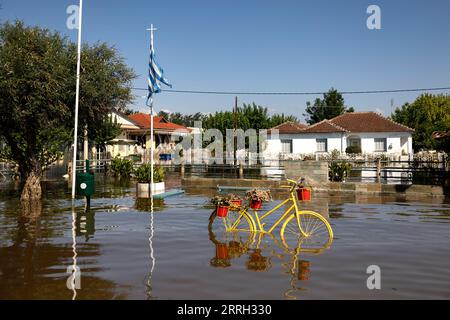 Karditsa, Griechenland. September 2023. Eine griechische Flagge fliegt über einem überfluteten Innenhof des Gesundheitszentrums im Dorf Palamas, in der Nähe der Stadt Karditsa, Zentralgriechenland. Die Zahl der Todesopfer durch Überschwemmungen, die durch sintflutartige Regenfälle in Zentralgriechenland verursacht wurden, ist weiter gestiegen. Quelle: Yorgos Karahalis/dpa/Alamy Live News Stockfoto