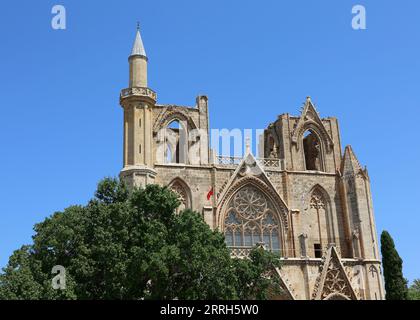 Lala Mustafa Pasa Camii Moschee alias Kathedrale des hl. Nikolaus mit Minarett und Fahnen in Famagusta, Zypern Stockfoto