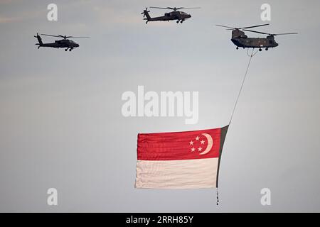 Hubschrauber im Flug, die die Flagge Singapurs für den Nationalfeiertag hinter sich lassen. Stockfoto