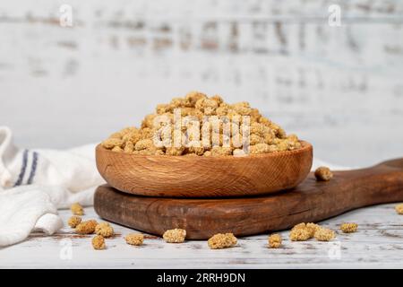 Getrocknete Maulbeeren in einer Holzschale. Sonnengetrocknete Maulbeere auf weißem Holzgrund Stockfoto