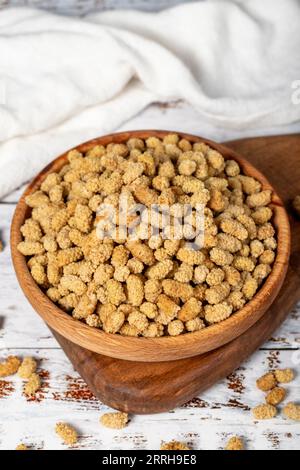 Getrocknete Maulbeeren in einer Holzschale. Sonnengetrocknete Maulbeere auf weißem Holzgrund Stockfoto