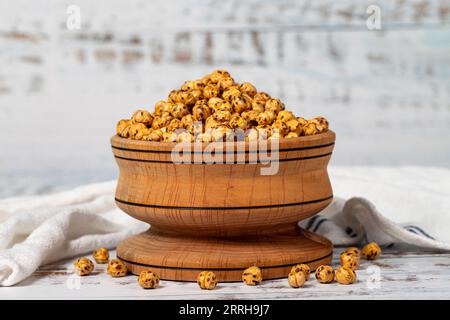 Geröstete Kichererbsen in einer Holzschale. Kichererbsen auf weißem Holzgrund Stockfoto