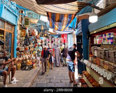 Tunis, Tunesien - 27. August 2022: Menschen, die in der Medina spazieren. Die Medina enthält etwa 700 Denkmäler, darunter Paläste, Moscheen und Mausoleen Stockfoto