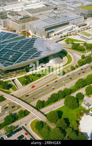 BMW-Hauptsitz in München, Deutschland, vom Olympiasturm aus gesehen, mit vorbeifahrenden Autos auf der angrenzenden Autobahn. Stockfoto