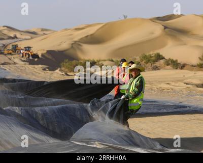 220630 -- YULI, 30. Juni 2022 -- Arbeiter arbeiten auf der Baustelle einer neuen Autobahn, die die Taklimakan-Wüste in der autonomen Region Xinjiang Uygur im Nordwesten Chinas durchquert, 5. Juli 2018. Die Autobahn, die Yuli County und Qiemo County verbindet, wurde am Donnerstag in Betrieb genommen und befindet sich im Süden der Mongolischen Autonomen Präfektur Bayingolin in Xinjiang. Die Autobahn ist die dritte über die Taklimakan-Wüste, die zweitgrößte Sandwüste der Welt. Mit einer Auslegungsgeschwindigkeit von 60 oder 80 km/h für verschiedene Abschnitte hat die Autobahn eine Gesamtlänge von 334 km, wobei 307 km durchfahren werden Stockfoto