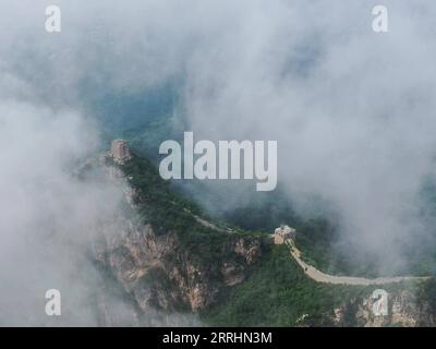 220704 -- PEKING, 4. Juli 2022 -- Luftaufnahme vom 4. Juli 2022 zeigt Wolken, die über der Chinesischen Mauer im Grenzgebiet zwischen dem Luanping County in der nordchinesischen Provinz Hebei und dem Bezirk Miyun in Peking, der Hauptstadt Chinas, schweben. CHINA-PEKING-GREAT WALL-LANDSCHAFT CN CHENXYEHUA PUBLICATIONXNOTXINXCHN Stockfoto