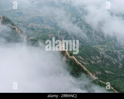 220704 -- PEKING, 4. Juli 2022 -- Luftaufnahme vom 4. Juli 2022 zeigt Wolken, die über der Chinesischen Mauer im Grenzgebiet zwischen dem Luanping County in der nordchinesischen Provinz Hebei und dem Bezirk Miyun in Peking, der Hauptstadt Chinas, schweben. CHINA-PEKING-GREAT WALL-LANDSCHAFT CN CHENXYEHUA PUBLICATIONXNOTXINXCHN Stockfoto