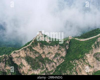 220704 -- PEKING, 4. Juli 2022 -- Luftaufnahme vom 4. Juli 2022 zeigt Wolken, die über der Chinesischen Mauer im Grenzgebiet zwischen dem Luanping County in der nordchinesischen Provinz Hebei und dem Bezirk Miyun in Peking, der Hauptstadt Chinas, schweben. CHINA-PEKING-GREAT WALL-LANDSCHAFT CN CHENXYEHUA PUBLICATIONXNOTXINXCHN Stockfoto