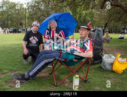 London, 8. september. 2023 der Royalist John Loughrey legt Blumen und eine Karte an die Wand des Buckingham Palace, um den ersten Todestag von Königin Elizabeth II. Zu feiern Und liegt auf Grün neben dem Buckingham Palace, mit Freunden, die Richard Lincoln/Alamy Live anschreiben Stockfoto