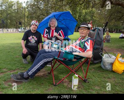 London, 8. september. 2023 der Royalist John Loughrey legt Blumen und eine Karte an die Wand des Buckingham Palace, um den ersten Todestag von Königin Elizabeth II. Zu feiern Und liegt auf Grün neben dem Buckingham Palace, mit Freunden, die Richard Lincoln/Alamy Live anschreiben Stockfoto