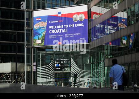 220713 -- BRÜSSEL, 13. Juli 2022 -- Ein Fußgängerspaziergang in der Nähe eines Posters Willkommen zum Euro, Kroatien in Brüssel, Belgien, 12. Juli 2022. Der kroatische Premierminister Andrej Plenkovic begrüßte am Dienstag die Entscheidung des Rates Wirtschaft und Finanzen der Europäischen Union (ECOFIN), Kroatien am 1. Januar 2023 in die Eurozone zu integrieren. BELGIEN-BRÜSSEL-EU-KROATIEN-EURO ZhengxHuansong PUBLICATIONxNOTxINxCHN Stockfoto