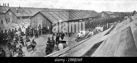 „L'Installation en France de L'Avant-Garde Americaine; UN bataillon du 16th Regiment d'infanterie americain fait son entr&#xe9;e dans le Camp musique en tete sous les yeux des Prisonniers allemands Affect&#xe9;s a la Construction des baraques“, 1917. Erster Weltkrieg: Die amerikanische Vorhut kommt in Frankreich an; ein Bataillon des 16. Infanterieregiments tritt unter den Augen der deutschen Kriegsgefangenen, die mit dem Bau der Kaserne beauftragt wurden, in das Lager ein, dem eine Militärband vorausgeht. Aus L’Album de la Guerre 1914-1919, Band 2 [L’Illustration, Paris, 1924]. Stockfoto